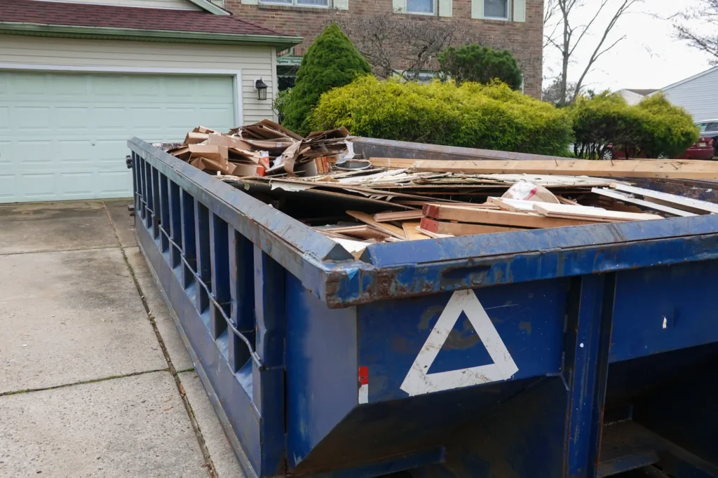 Roll-off dumpster in a driveway for heavy debris cleanup.